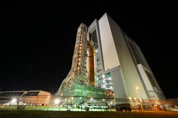 NASAs next-generation moon rocket, the Space Launch System rocket with its Orion crew capsule perched on top, leaves the Vehicle Assembly Building