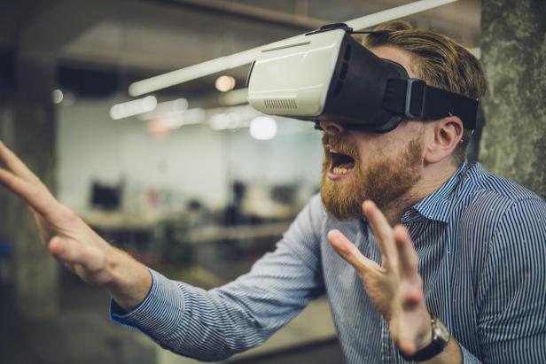 Young entrepreneur having fun on a break while using virtual reality simulator.