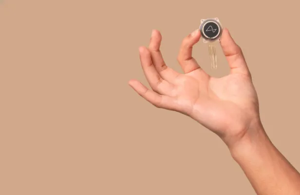 Der Gehirnchip von Neuralink wird von einer Hand gehalten. 