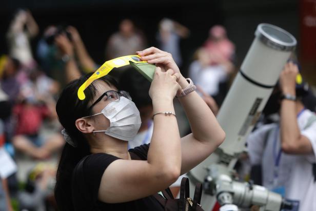 People watch the hybrid solar eclipse in Jakarta