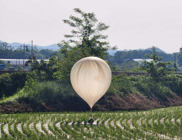 FILE PHOTO: A balloon believed to have been sent by North Korea, carrying various objects including what appeared to be trash and excrement, is seen over a rice field at Cheorwon