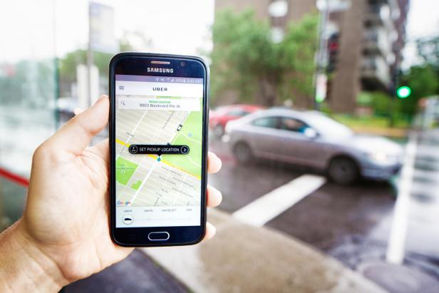 Personal perspective view of hand holding phone ordering Uber ride