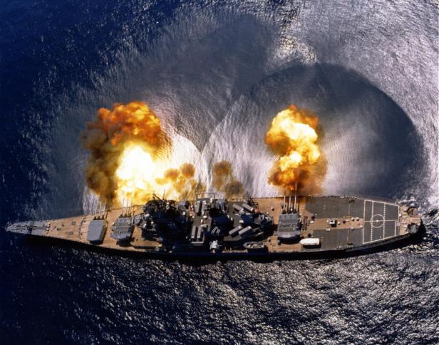 Ein Schlachtschiff der Iowa-Klasse feuert seine schweren Geschütze auf dem offenen Meer ab.