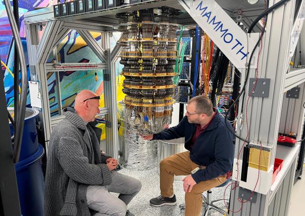 Google Quantum AI's Hartmut Neven (L) and Anthony Megrant (R) examine a cryostat refrigerator for cooling quantum computing chips at Google's Quantum AI lab in Santa Barbara