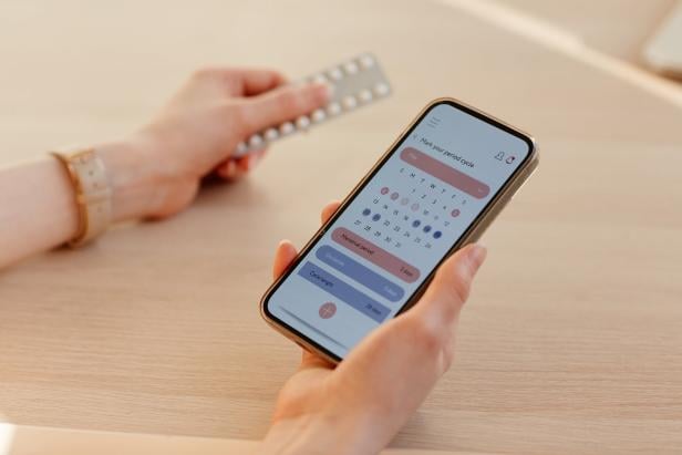 Tracking App for Birth Control Frau hält Handy und nutzt Zyklus-App.