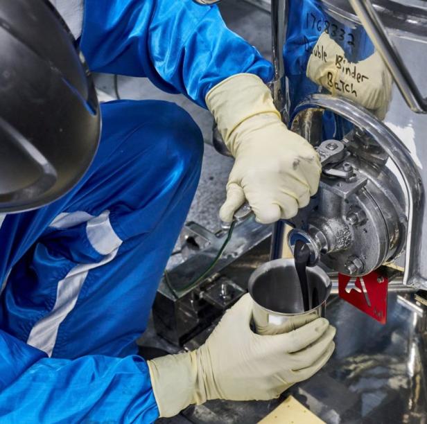 Ein Batterietechniker im Wallace Battery Cell Innovation Center von General Motors entnimmt eine Probe des chemischen Schlamms. 