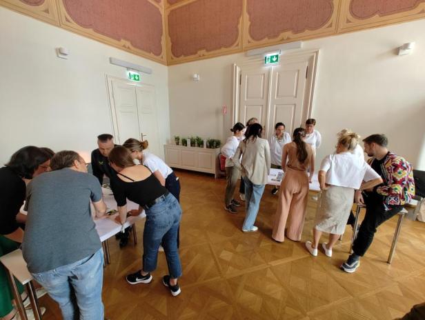 Eine Gruppe von Menschen arbeitet gemeinsam an einem Workshop-Tisch.