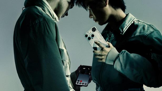 Zwei Personen betrachten zwei „Nothing Phone“-Smartphones.