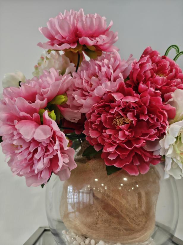 Ein Arrangement aus rosa und roten Pfingstrosen in einer Glasvase.