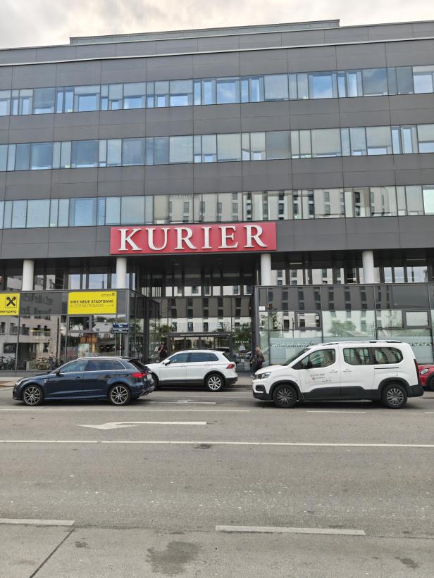 Das Kurier-Gebäude in Wien mit geparkten Autos davor.