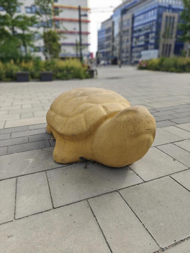Eine steinerne Schildkröte dient als Dekoration in einer Fußgängerzone.