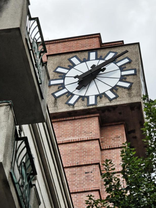 Eine große Uhr an einem Gebäude mit Ziegel- und Betonfassade.