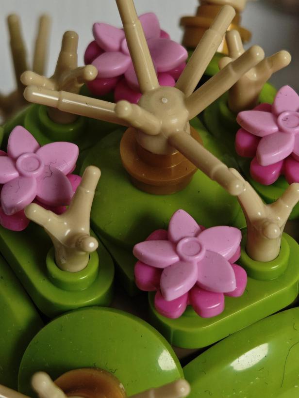 Ein Lego-Blumenarrangement mit rosa Blüten und grünen Blättern.