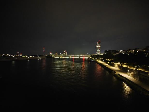 Ein akzeptables Nachtfoto einer Stadtlandschaft mit einem Fluss und beleuchteten Gebäuden.