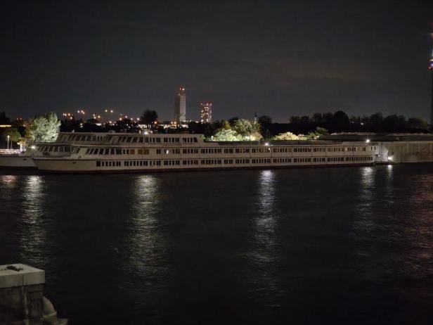 Ein großes Passagierschiff liegt nachts auf einem Fluss vor Anker.