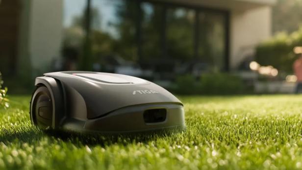 Ein grauer Rasenmähroboter der Marke Stiga steht auf einem Rasen.