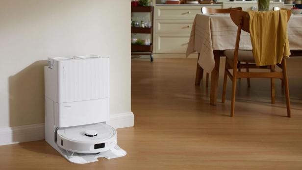 Ein Roborock Saugroboter steht in einer Ladestation in einem Wohnraum.