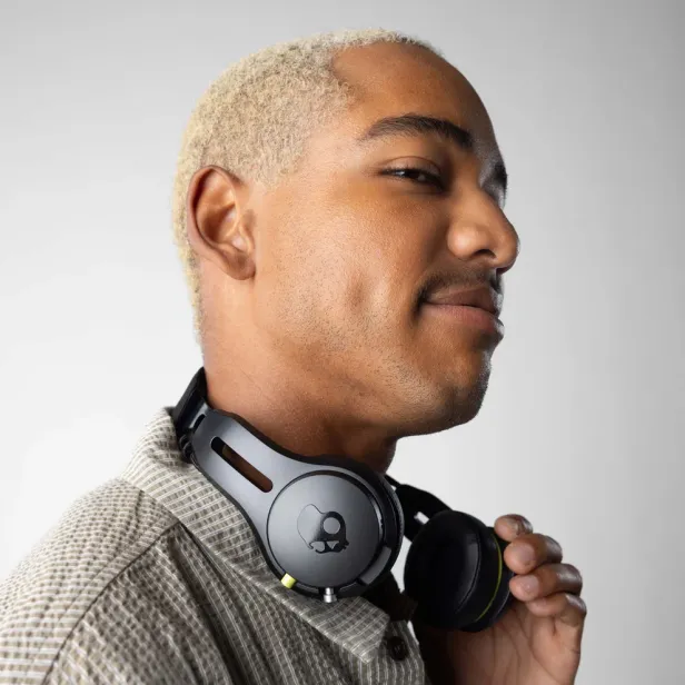 Ein Mann mit blond gefärbten Haaren und Skullcandy-Kopfhörern um den Hals.