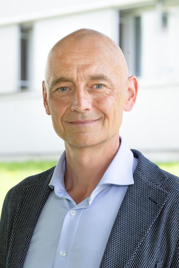 Porträt eines Mannes mit hellblauer Bluse und dunklem Sakko.