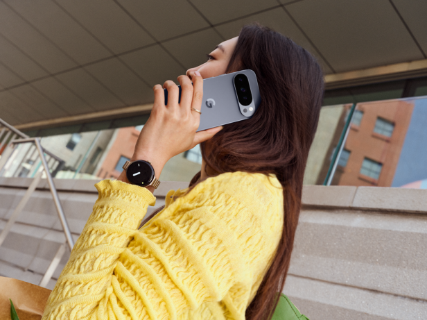 Eine Frau telefoniert mit einem Google Pixel Smartphone und trägt eine Smartwatch.