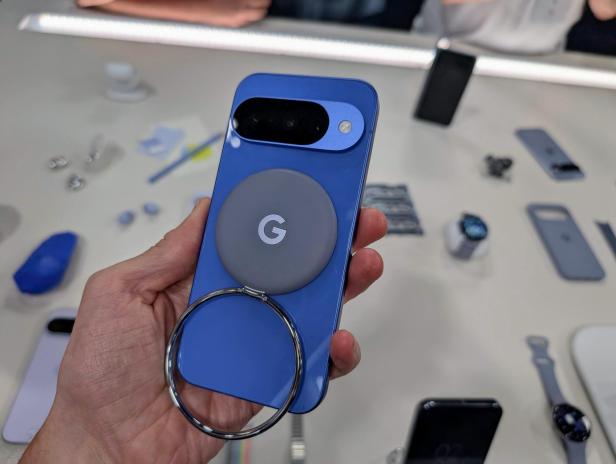 Ein blaues Google Pixel-Smartphone mit einem MagSafe-kompatiblen Zubehör in der Hand.