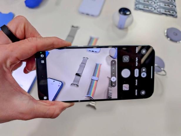 Eine Hand fotografiert mit einem Smartphone verschiedene Armbänder und Zubehör für Smartwatches.