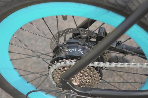 Das Hinterrad eines Boost-Fahrrads mit blauem Felgenband und Kettenschaltung.