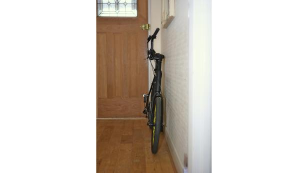 Ein schwarzes Fahrrad mit gelben Akzenten steht an einer Wand.