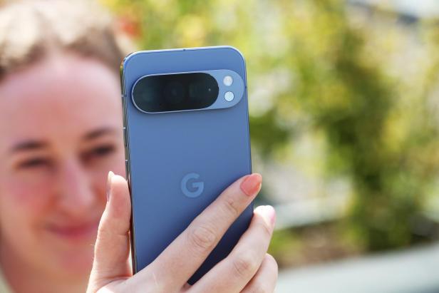 Eine Frau hält ein blaues Google Pixel Smartphone in der Hand.
