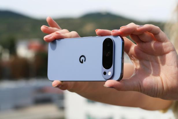 Eine Person hält ein blaues Smartphone mit der Aufschrift „G“ in der Hand.