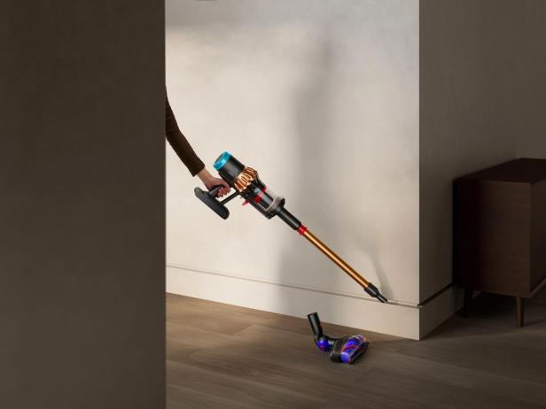 Eine Person saugt mit einem Dyson-Akku-Staubsauger den Boden.