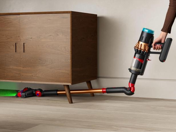 Ein Dyson V16 Staubsauger wird unter einem Holzschrank verwendet.