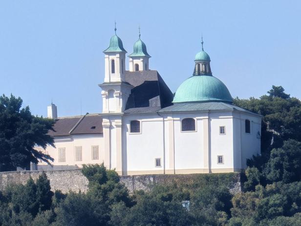 Ein weißes Gebäude mit einem grünen Kuppeldach und zwei Türmen steht auf einem Hügel.