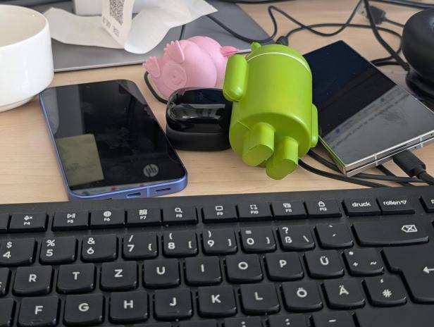 Ein Schreibtisch mit zwei Smartphones, einer Tastatur und einer Android-Figur.