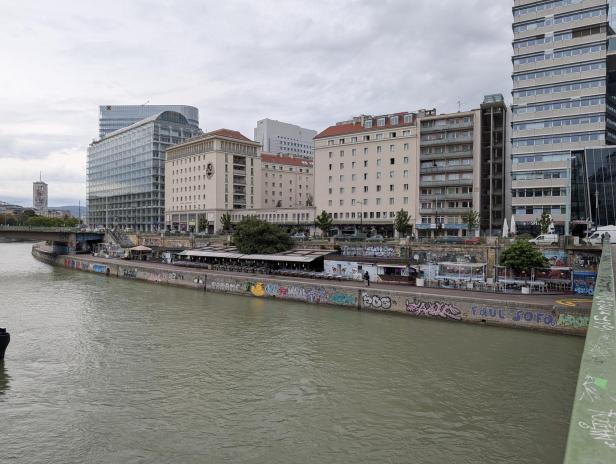 Die Donau fließt durch Wien, gesäumt von Gebäuden und Graffiti.