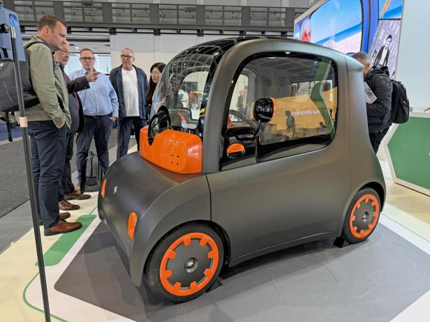 Ein elektrisches Microcar von Astraux wird von mehreren Personen betrachtet.