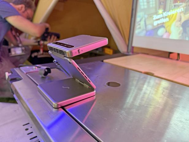 Ein Mini-Beamer der Marke Aurzen ZIP projiziert ein Bild an die Zeltwand.