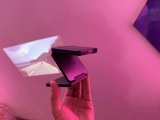 Ein Mini-Beamer der Marke Aurzen ZIP projiziert ein Bild an eine Wand.