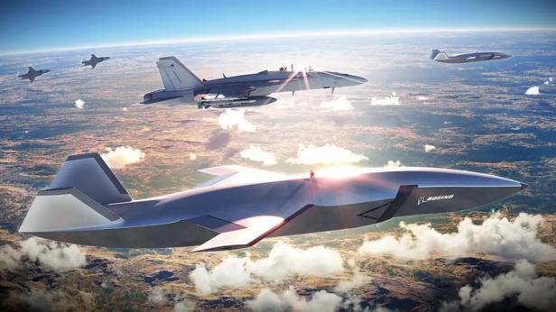 Mehrere Boeing MQ-28 Ghost Bat Drohnen im Flug über einer bewaldeten Landschaft.