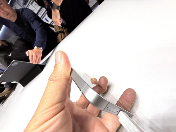 Eine Hand hält ein silbernes Smartphone mit Ladekabel.