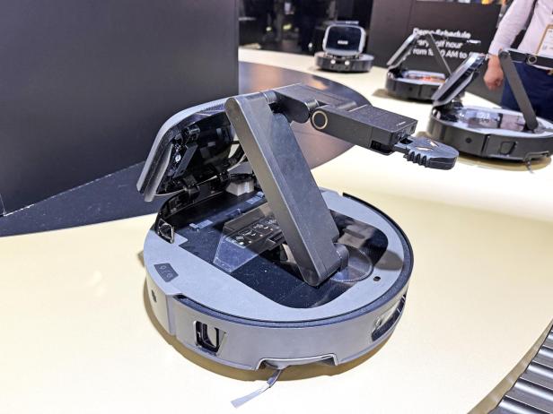 Der Dreame Cyber 10 Ultra Saugroboter mit geöffnetem Deckel und ausgefahrenem Arm.