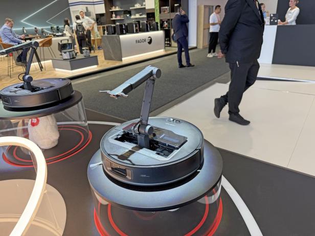 Ein Roborock Saugroboter Saros Z70 mit ausfahrbarem Arm auf einem Messestand.
