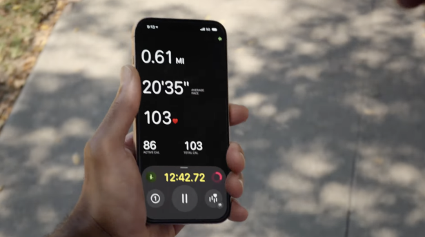 Eine Person hält ein iPhone, das eine Fitness-App mit Trainingsdaten anzeigt.