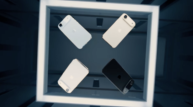 Vier iPhones, darunter ein schwarzes, sind in einem beleuchteten Rahmen angeordnet.