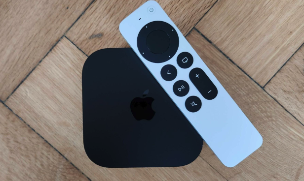 Ein Apple TV 4K mit zugehöriger Fernbedienung auf einem Holztisch.