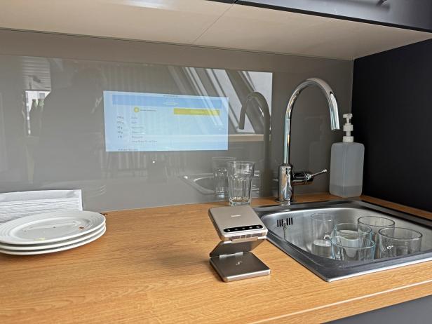 Eine Aurzen ZIP Küchenwaage steht vor einer Küchenspüle, auf der ein Rezept projiziert wird.