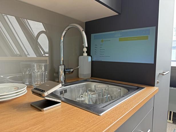 Eine Küche mit Spüle, Geschirr und einem Bildschirm, der ein Backrezept anzeigt.