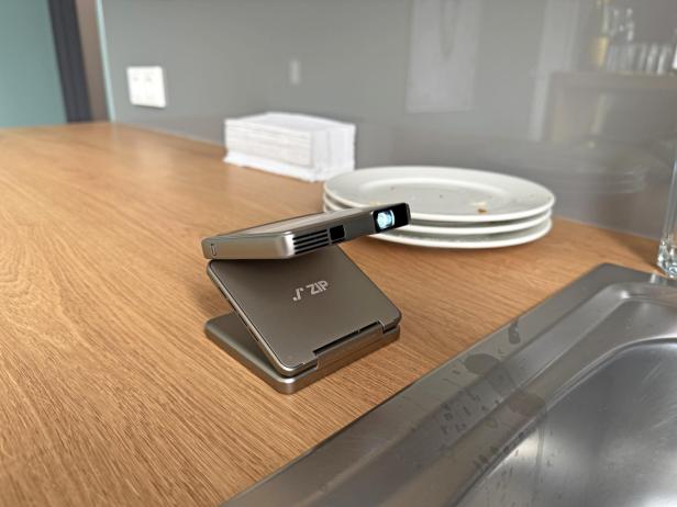 Ein tragbarer ZIP-Projektor steht auf einem Holztisch.