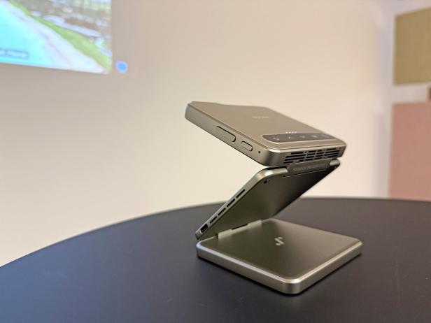 Ein tragbarer Aurzen ZIP-Projektor steht auf einem Tisch und projiziert ein Bild an die Wand.