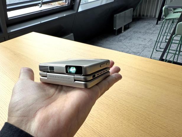 Ein Mini-Projektor liegt in einer Hand.
